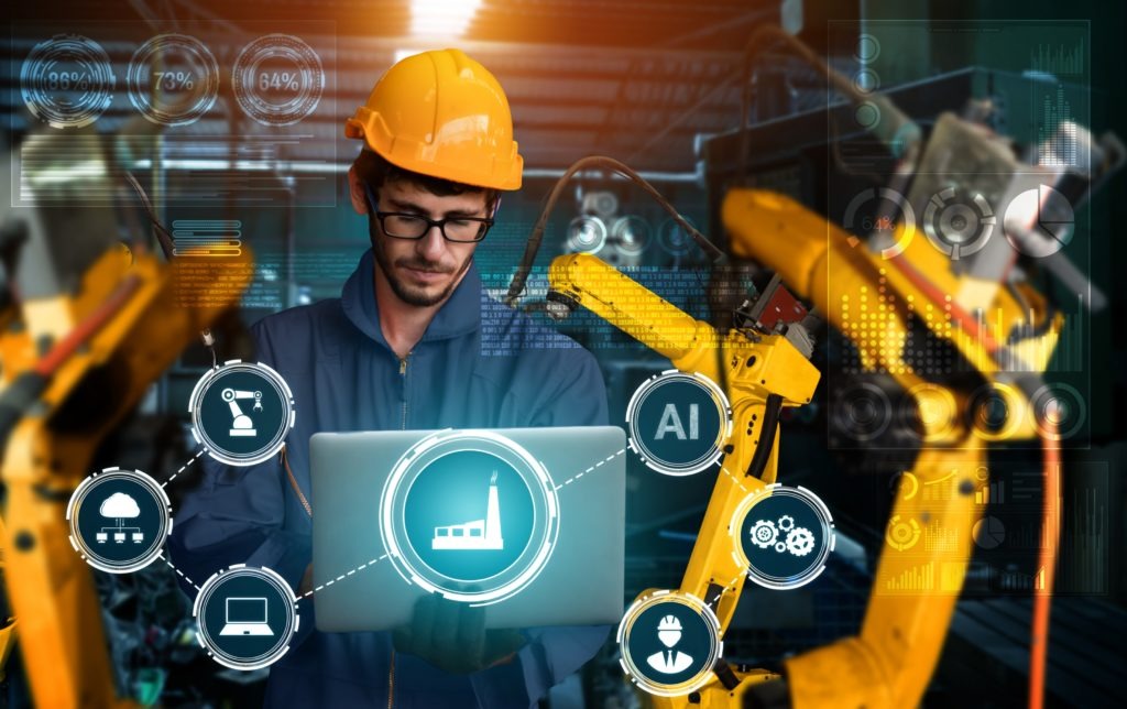 Inżynier z laptopem na tle ramion robotycznych w inteligentnej fabryce